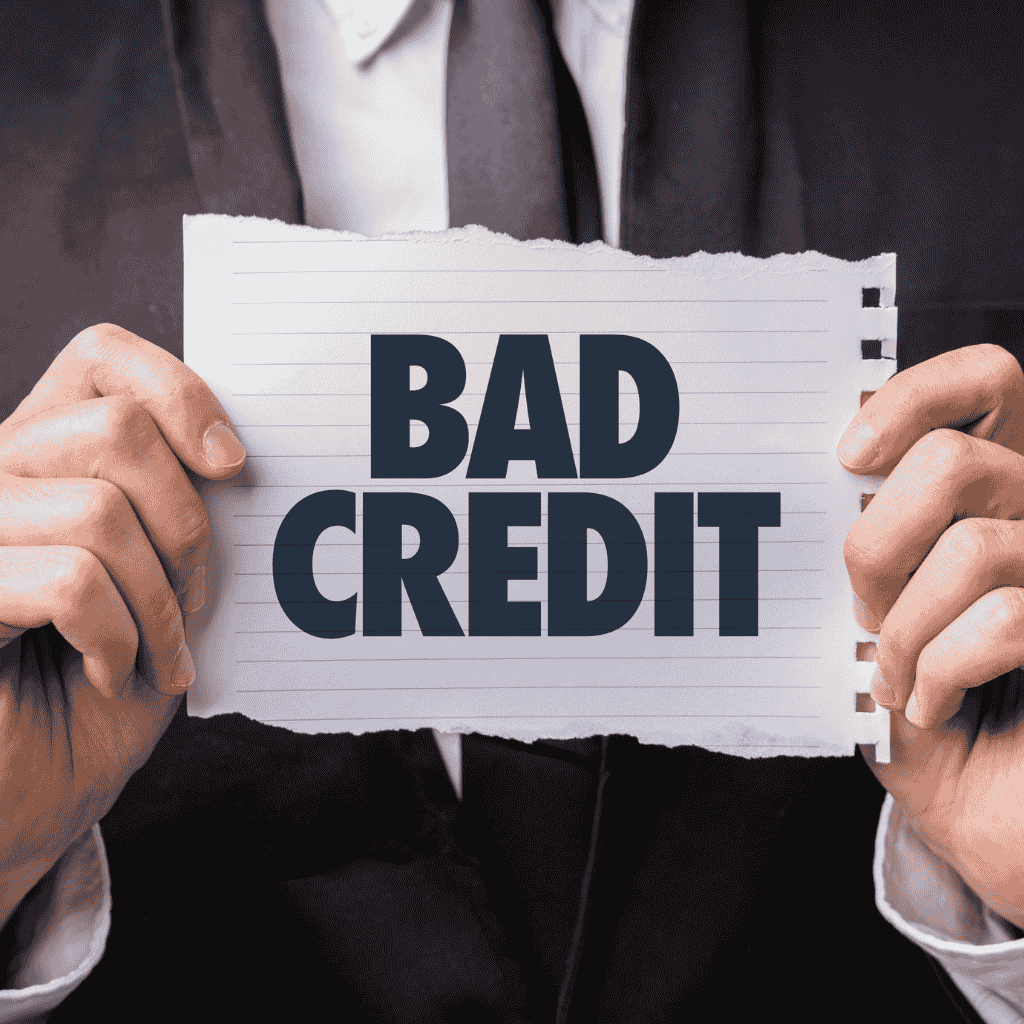 Person holding a paper with “Bad Credit” written on it, symbolizing financial struggles or low credit score.